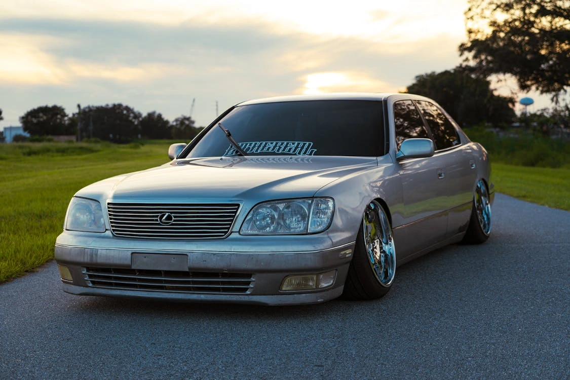 Silver luxury car parked on a country road at sunset
