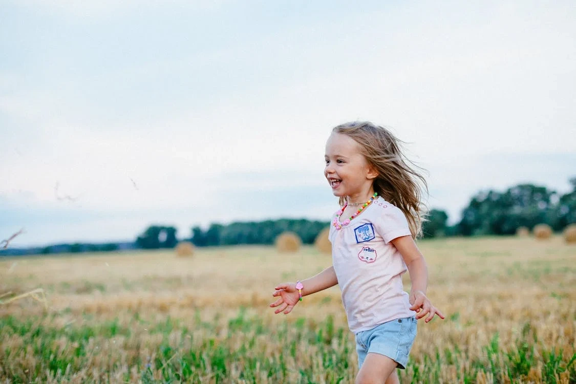 Smiling girl running across a green field on a sunny day
