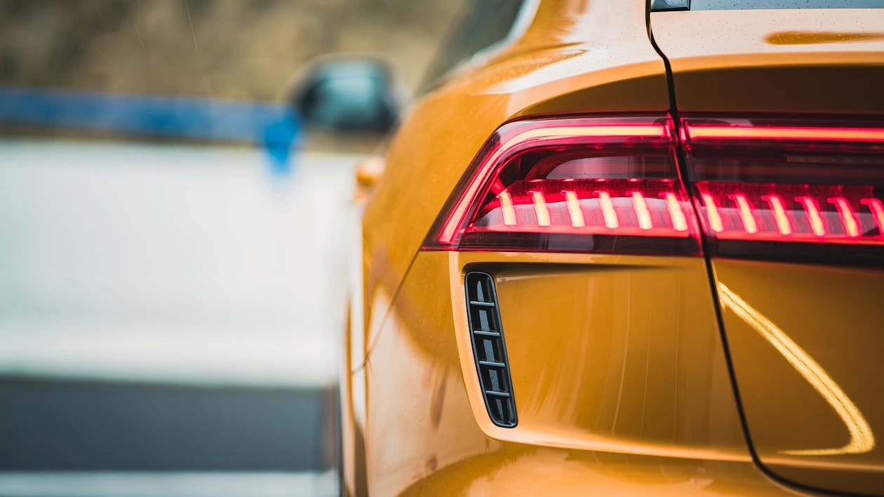 Close-up of a sleek yellow car’s taillight outdoors
