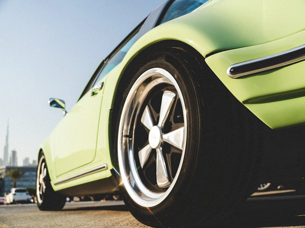 Vintage green sports car parked in an urban setting during daytime
