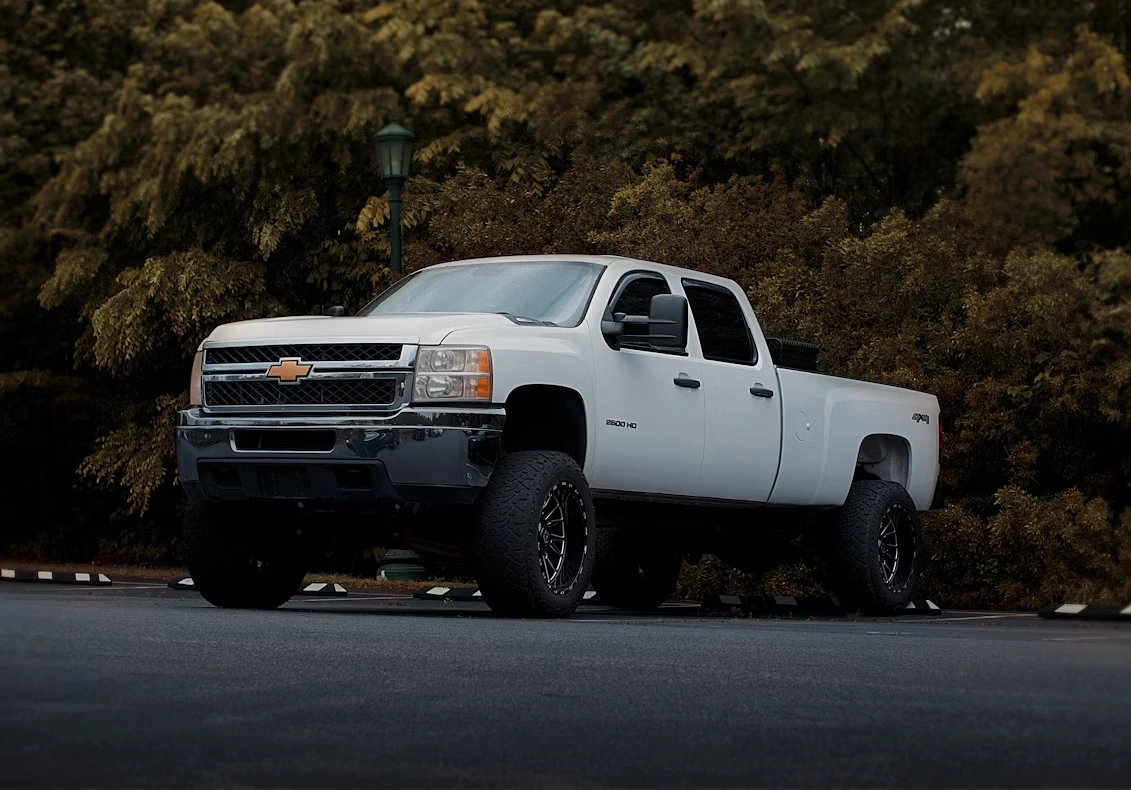 White pickup truck parked in front of trees during daytime