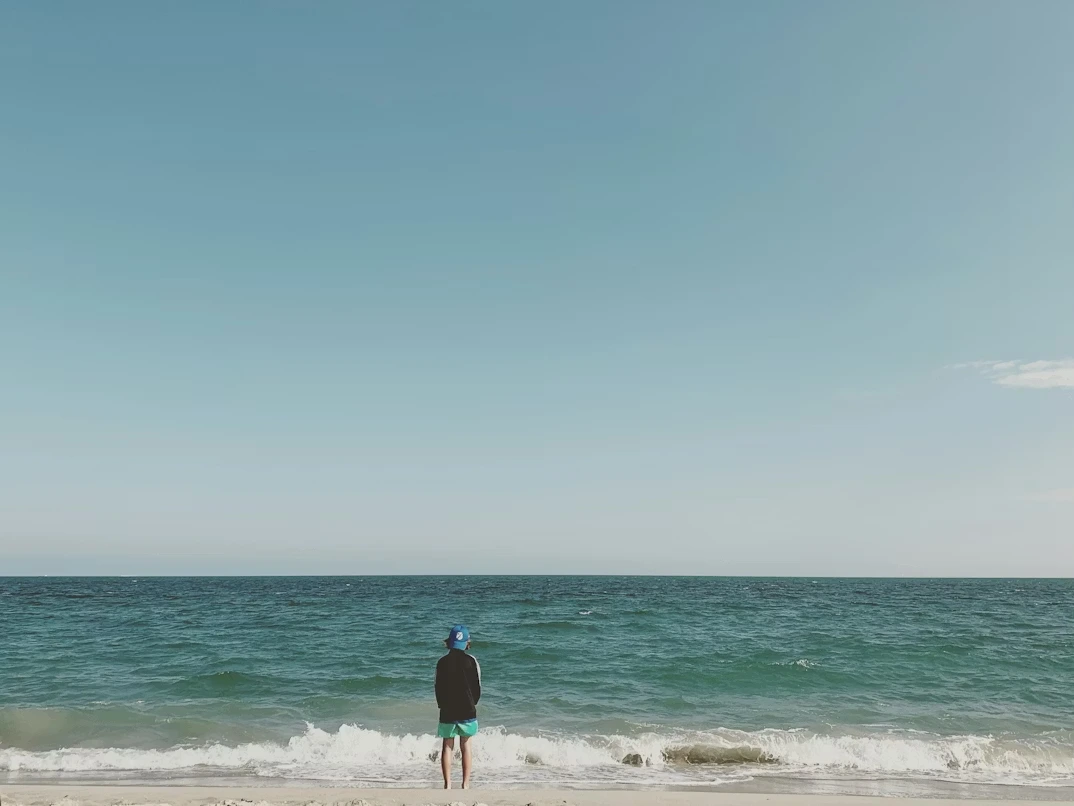 Person in a black shirt and green pants standing on the beach during daytime in Long Beach, NY