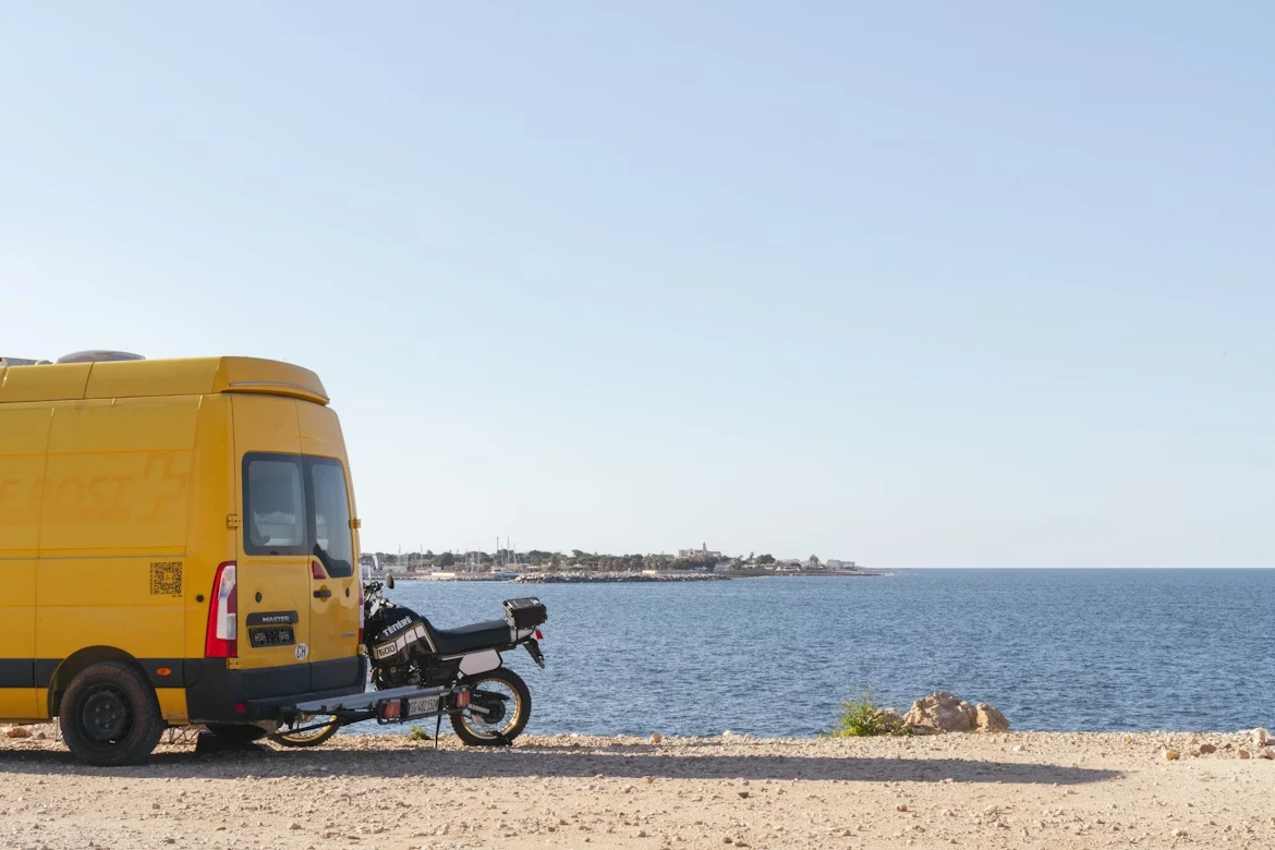 Yellow van and motorcycle near the ocean