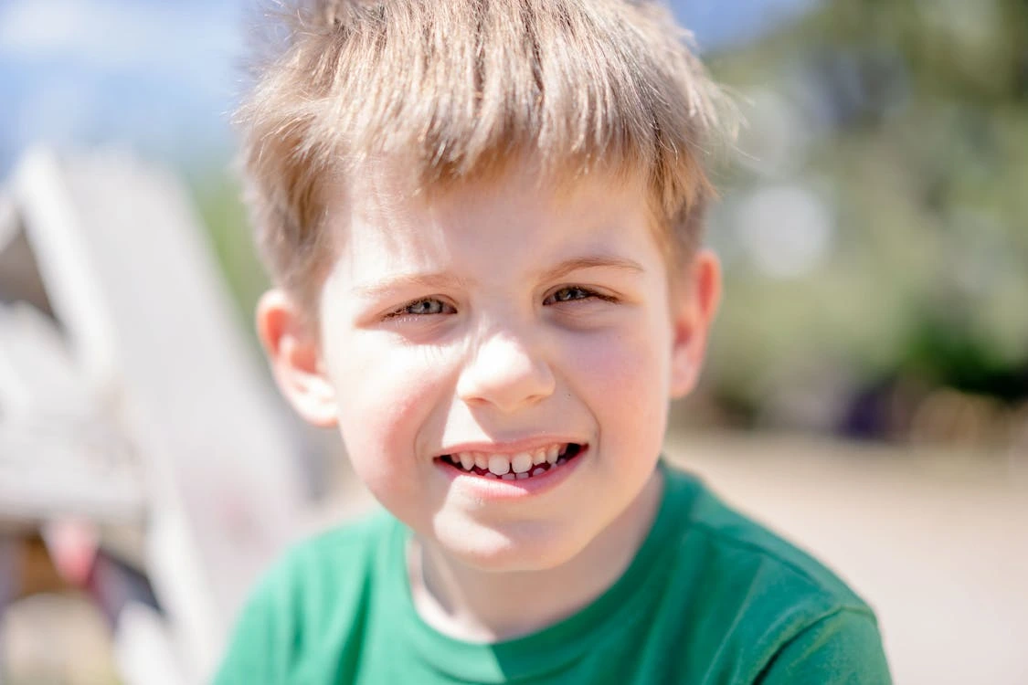 Smiling boy in a green crew-neck shirt outdoors