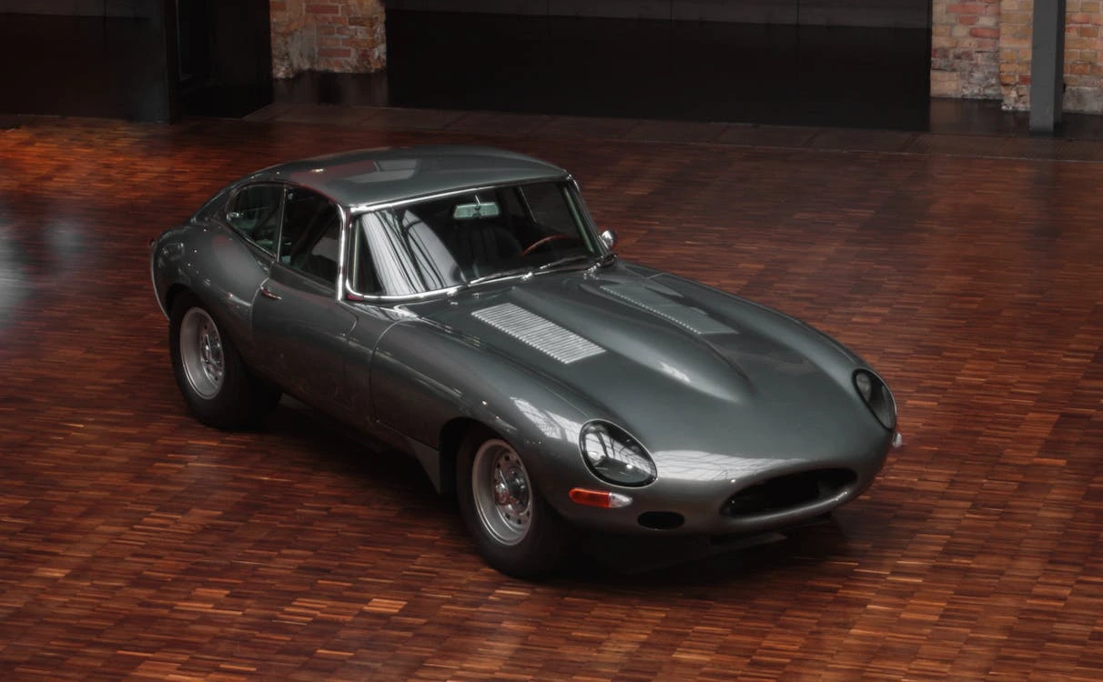 Gray sports car parked on a brown wooden floor in a showroom