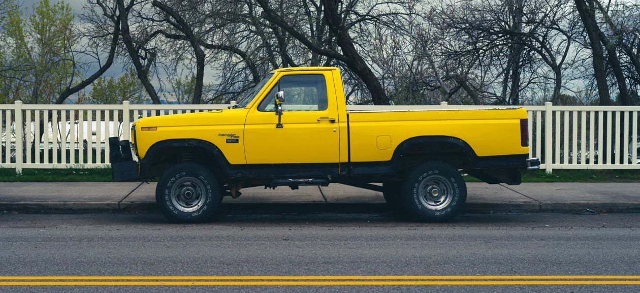 Yellow vintage pickup truck parked on a roadside in a rural setting